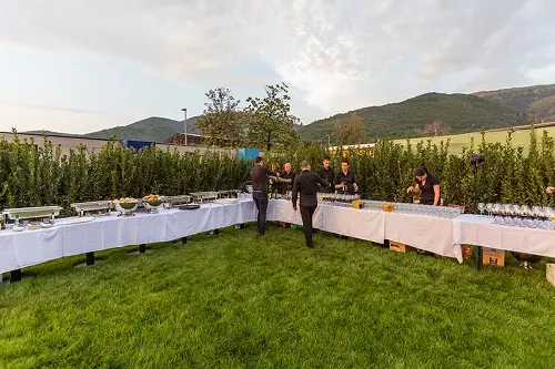 long white tables with food standing outside